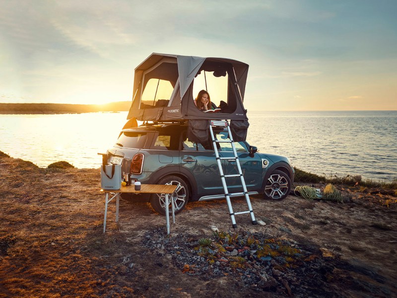 Dachzelt von Dometic auf einem Mini Cooper montiert, der auf einer Steilüste über dem Meer stehtr.