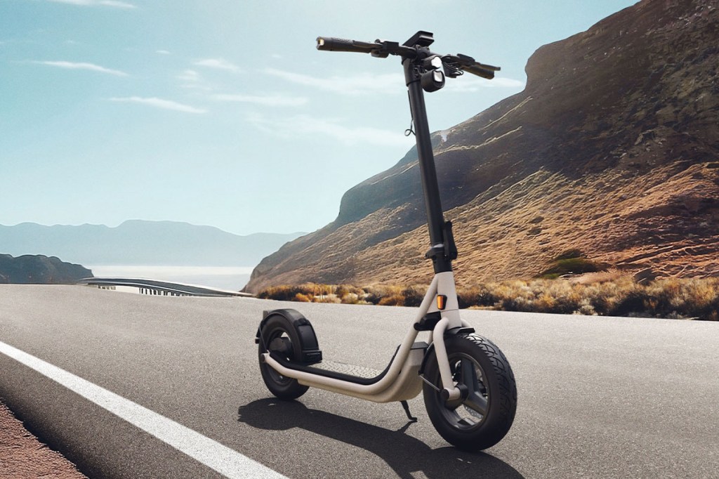 weißer E-Scooter steht auf einer einsamen Straße, hügelige Region im Hintergrund