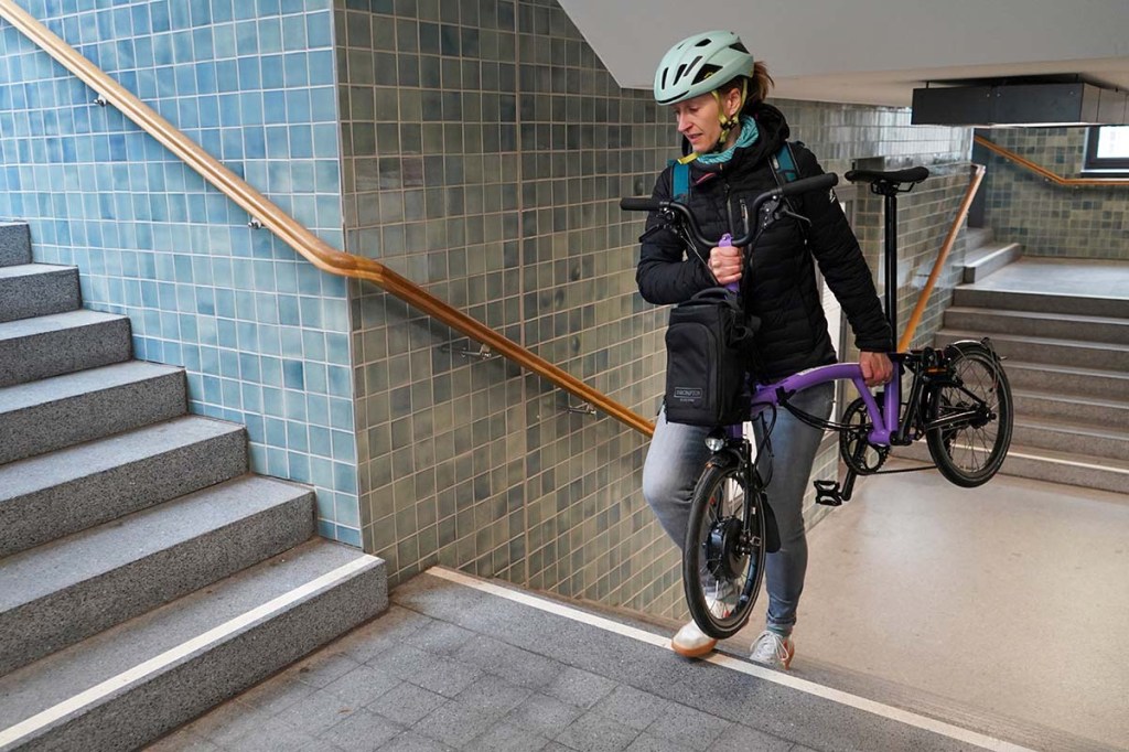 Frau trägt Fahrrad eine U-Bahn Treppe hoch