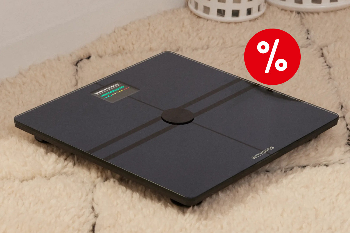 Schwarze quadratische Withings-Waage schräg von oben auf hellem Teppich mit rotem Prozentbutton oben rechts