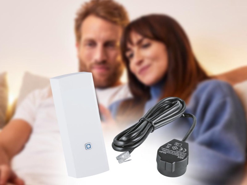 Im Vordergrund die Energieschnittstelle von Homematic IP, im Hintergrund ein Paar auf der Couch.