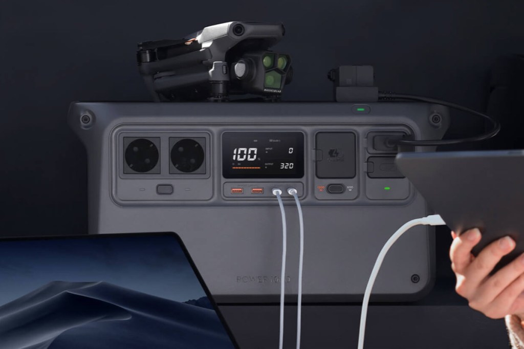 Die DJI Power 100 in einem Kofferraum mit angeschlossenen Geräten und einer Drohne oben drauf.