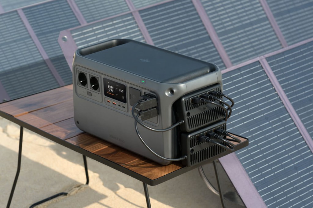 Die Power 1000 von DJI mit zwei angeschlossenen Adapter-Modulen und Solarpanels im Hintergrund.