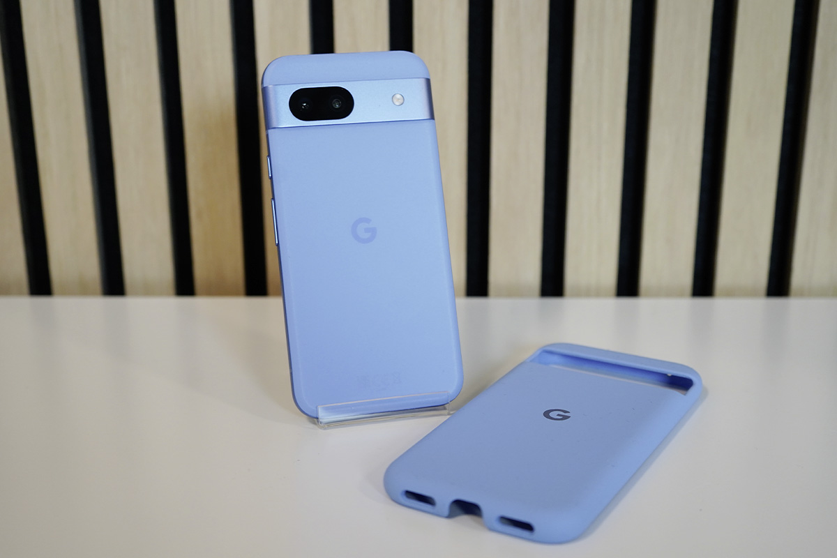 Ein hellblaues Smartphone auf einem weißen Tisch vor einer Wand mit heller Holzverkleidung.