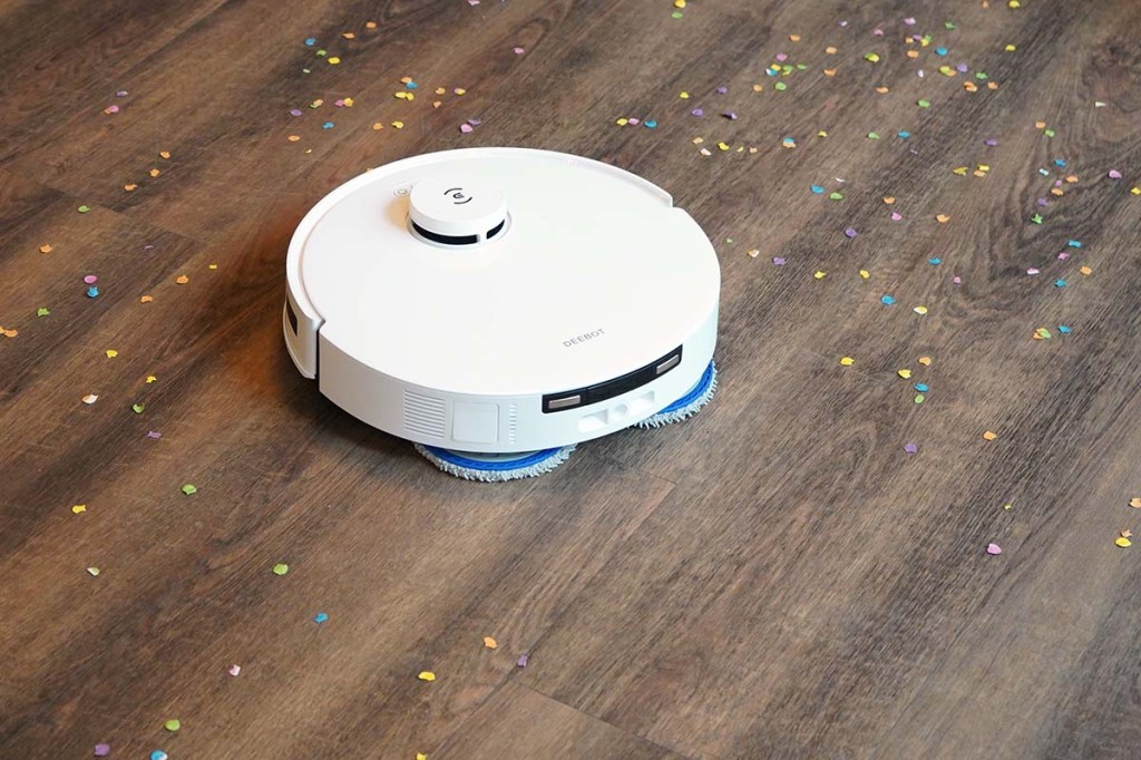 Der Deebot T30 Pro Omni auf einem Holzfußboden mit Konfetti.