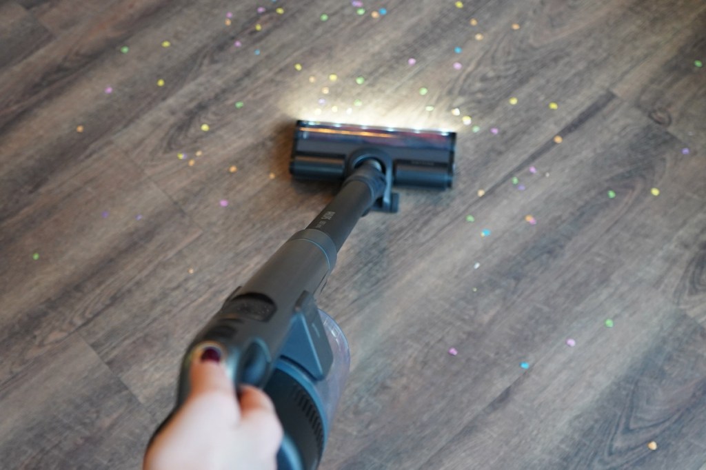 Der Philips-Akkusauger von oben beim Saugen eines Holzfußbodens mit Konfett.