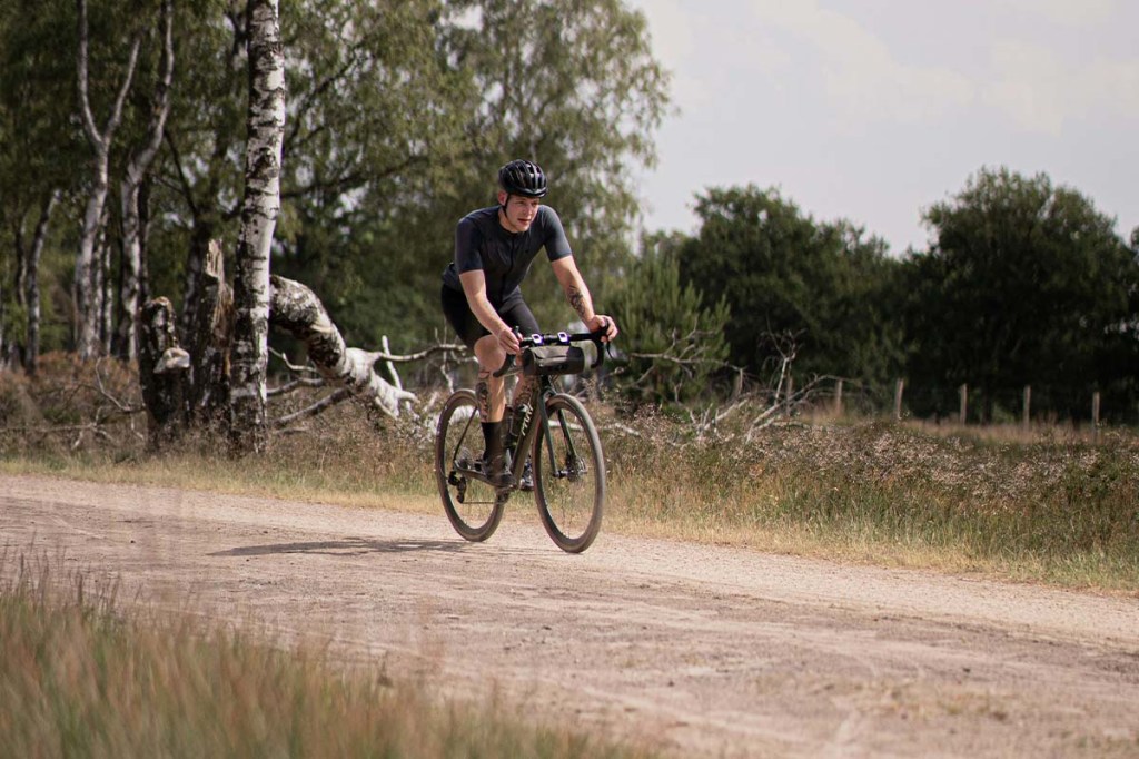 Mann fährt mit einem Gravelbike über einen SChotterweg