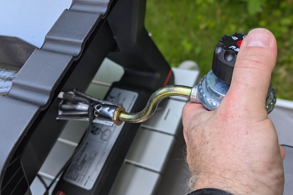 Eine Hand, die den Druckminderer bei einem der Cmapinggrills befestigt