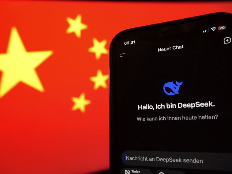 Ein smartphone mit der DeepSeek-App vor der Staatsflagge der Volksrepublik China auf einem Monitor.