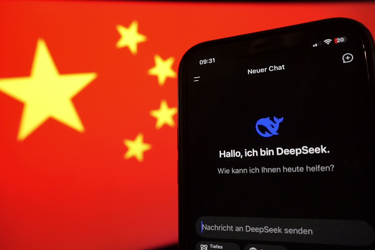 Ein smartphone mit der DeepSeek-App vor der Staatsflagge der Volksrepublik China auf einem Monitor.