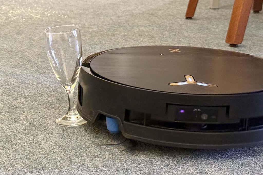 Der Deebot X9 Pro Omni in wohnlicher Umgebung. Daneben ein schräges Trinkglas.