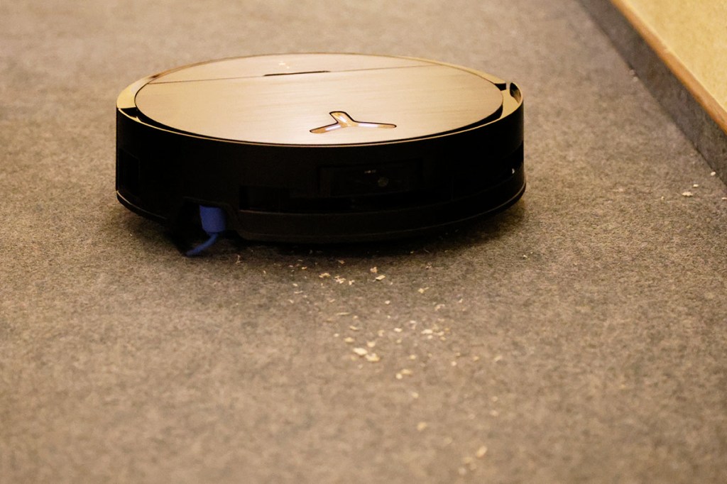 Der Ecovacs Deebot X9 Pro Omni auf Teppichboden mit Testschmutz vor sich.