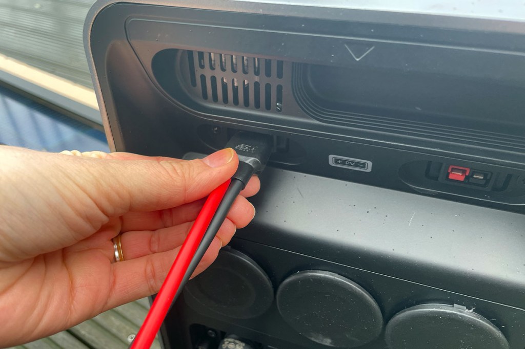 Eine Hand steckt ein Kabel an die VitaPower von Alpha ESS.