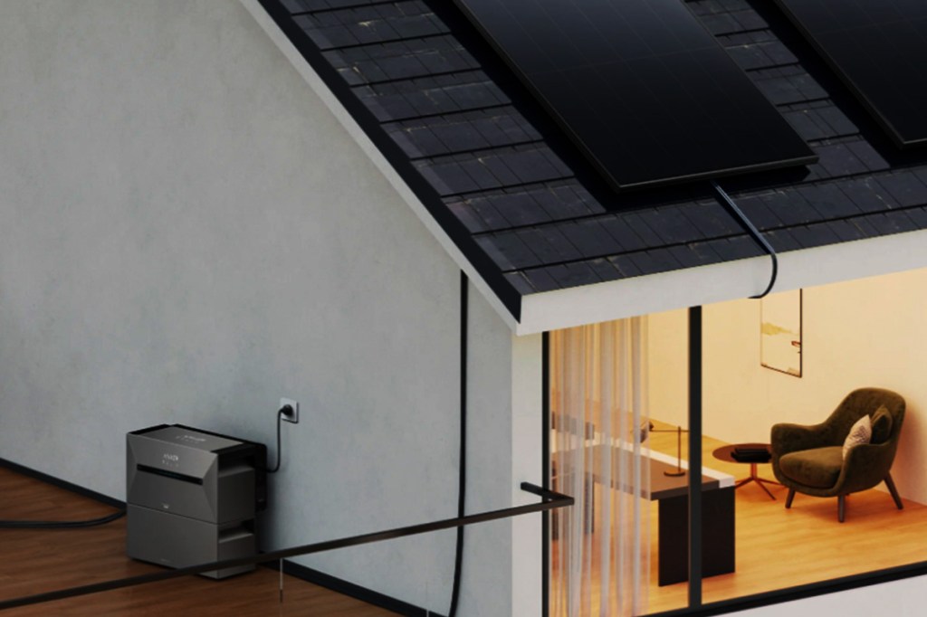 Ein Haus mit Terrasse. Auf dem Dach sind Solarpanels, seitlich am Haus ein Speicher. Außen ist es dunkel, drinnen brennt Licht.