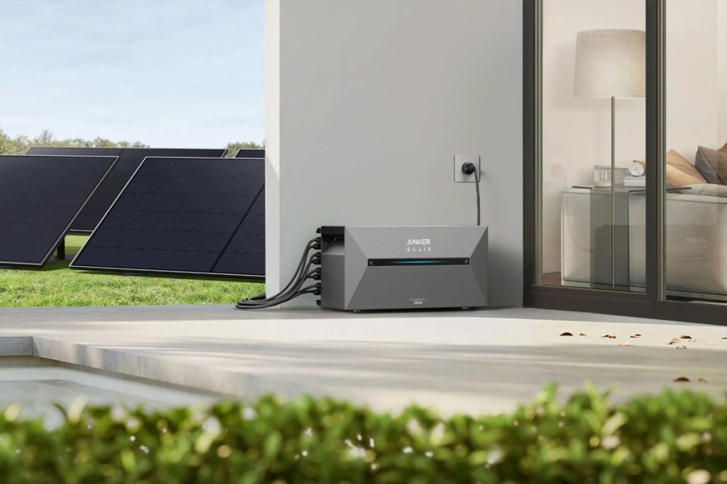 Die Anker Solix Solarbank 2 E1600 Pro auf einer Terrasse mit Solarmodulen im Hintergrund.