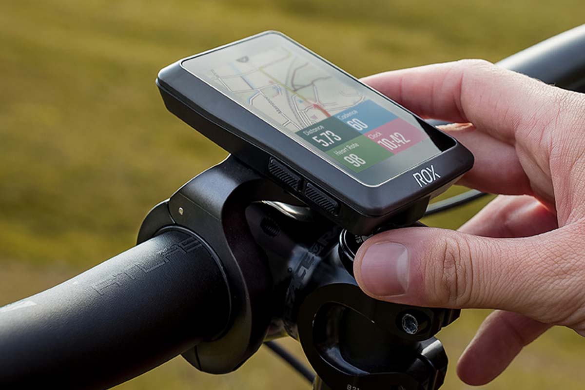 Nahaufnahme Navi an einem Fahrradlenker, das von einer Hand festgehalten wird