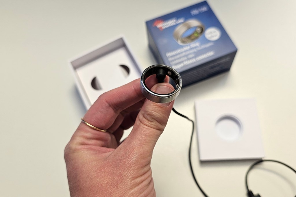 Hand hält einen Smart Ring, der an einem Kabel ist