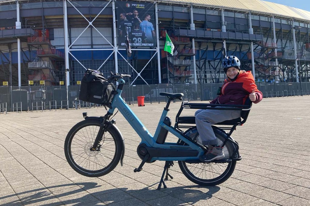 Lastenrad vor einem Stadion stehend, ein Kind sitzt auf dem Gepäckträger