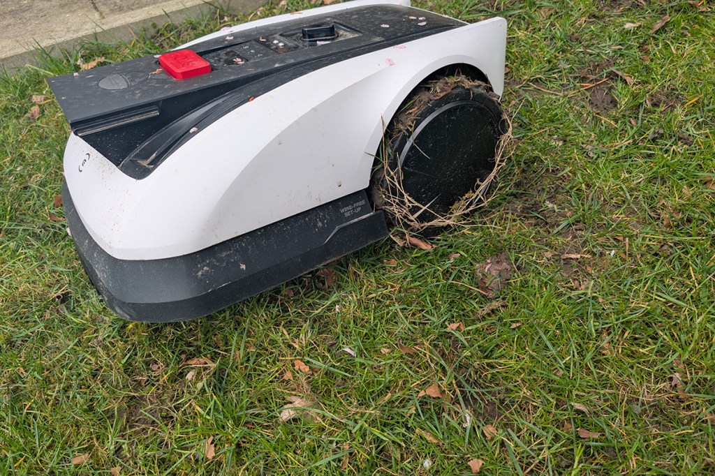 Mähroboter mit viel Gras und Schlamm auf den Rädern