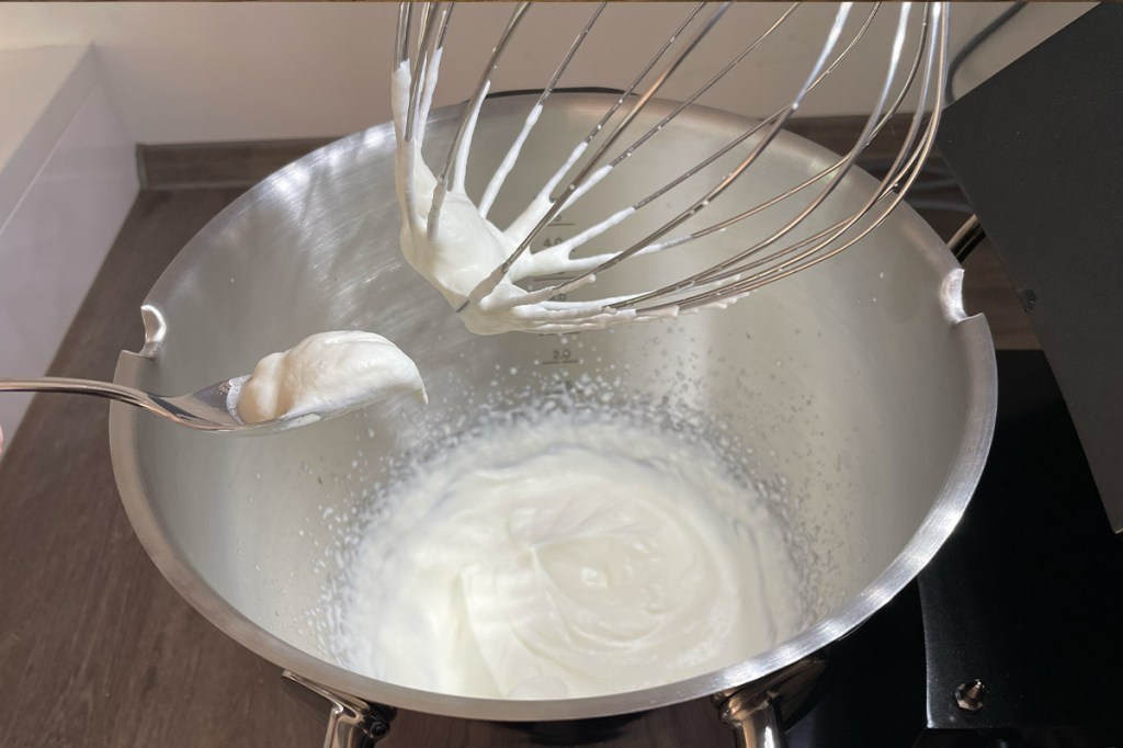 Schlagsahne in der Mixschüssel des Kenwood Cooking Chef Sallys Edition. Etwas Sahne ist zudem am Schneebesen und an einem Teelöffel.