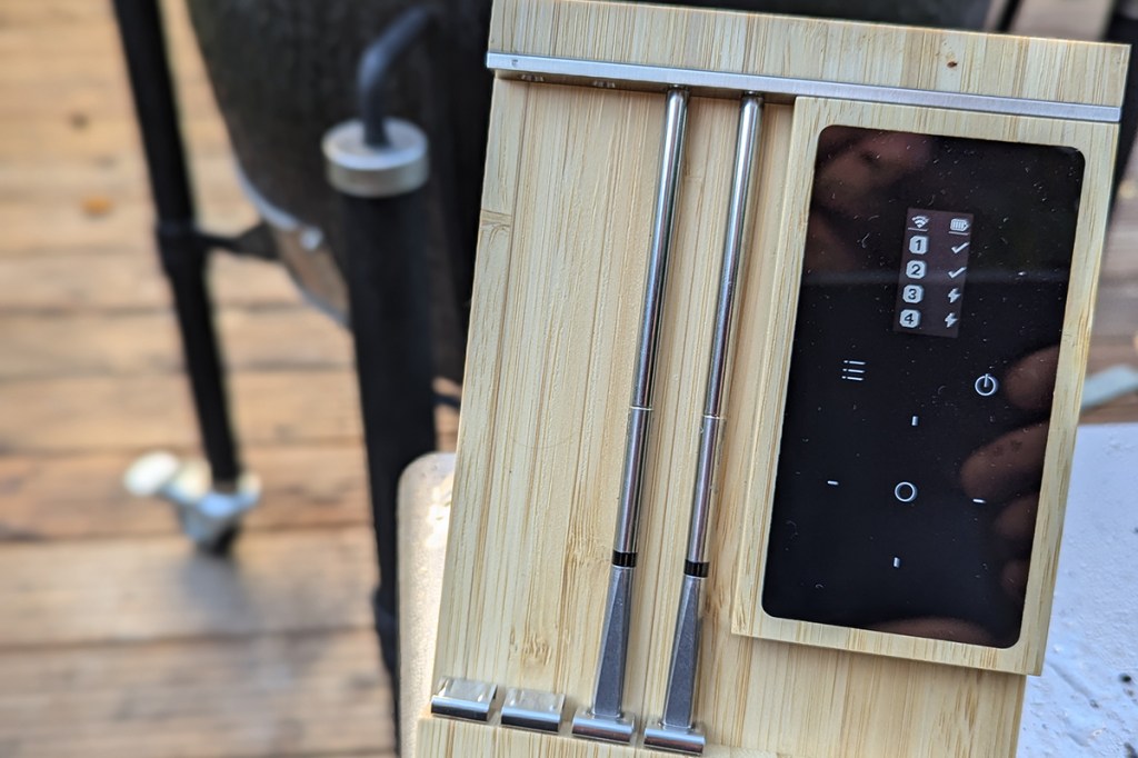 Ein kabelloses Grillthermometer neben einem Grill
