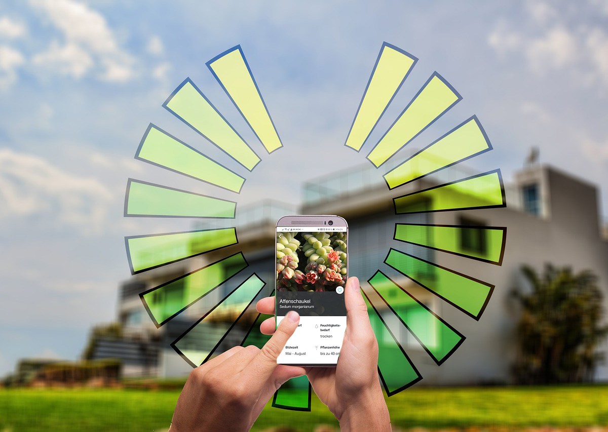 Eine Hand mit Smartphone vor einem Haus
