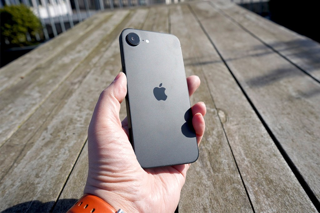 Eine Hand hält ein iPhone 16e hoch.