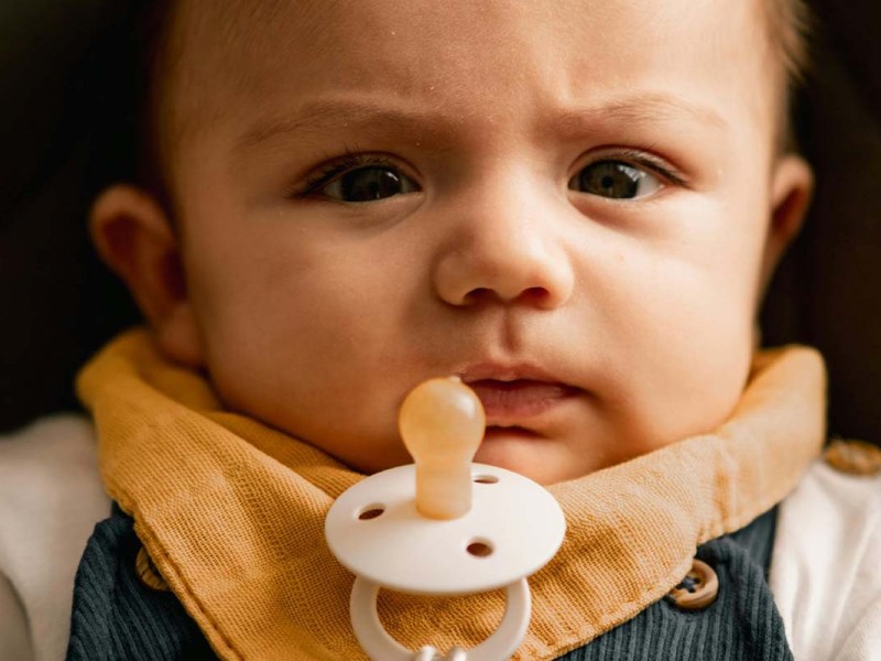 Nahaufnahme eines Babys, es hat vor seinem Mund einen SChnuller