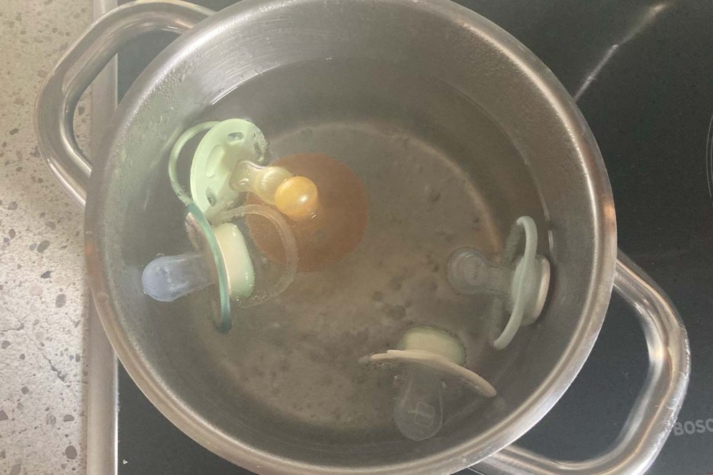 Blick in einen Kochtopf, in dem fünf Schnuller abkochen