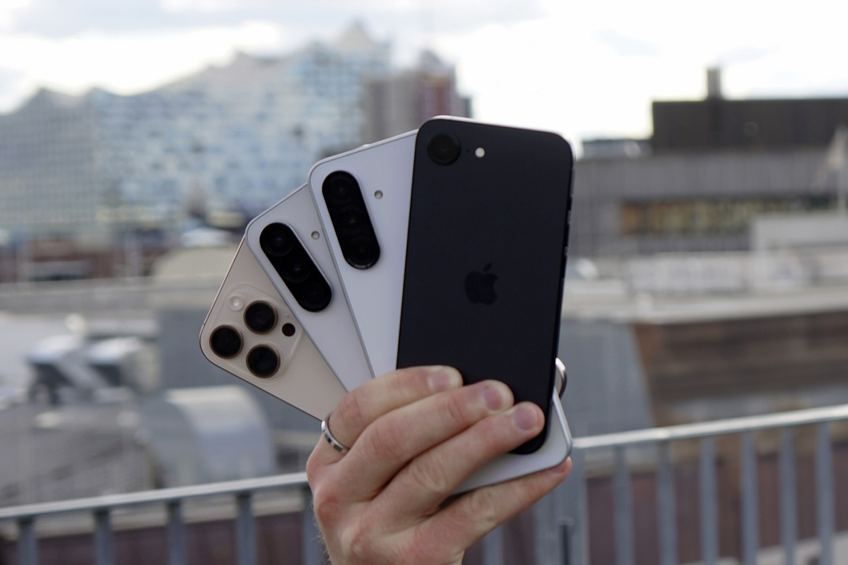 Eine Hand hält vier Smartphones hoch.