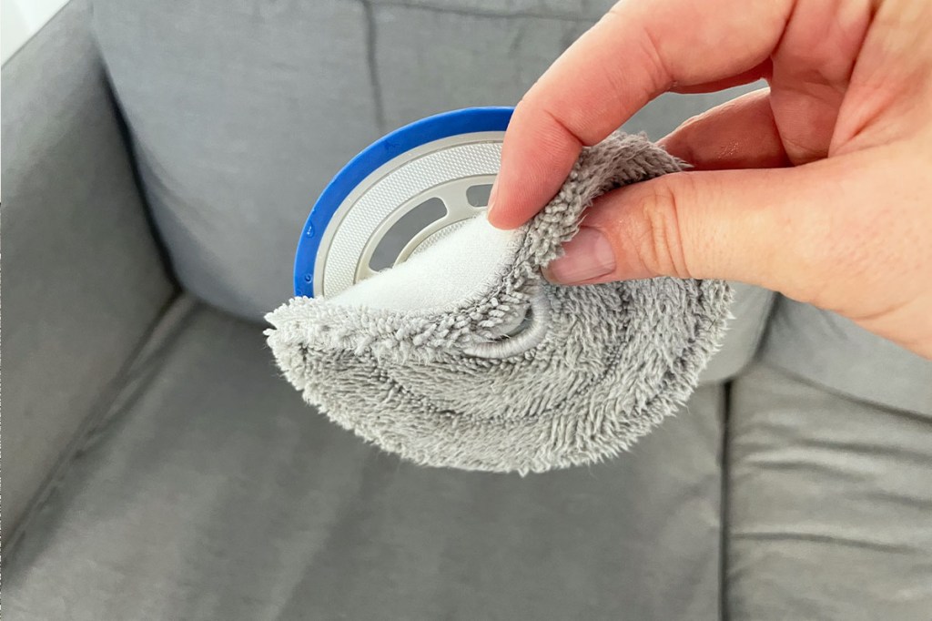 Eine Hand entfernt das Wischtuch des Deebot mini von seiner Halterung.