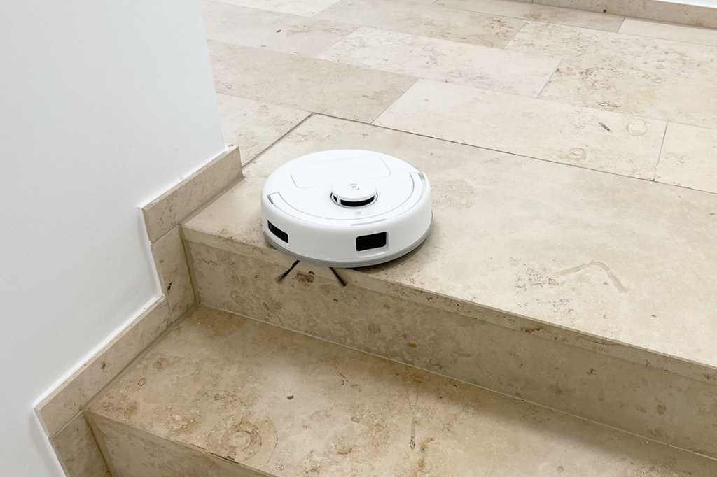 Der Deebot mini am Rand einer Treppenstufe.