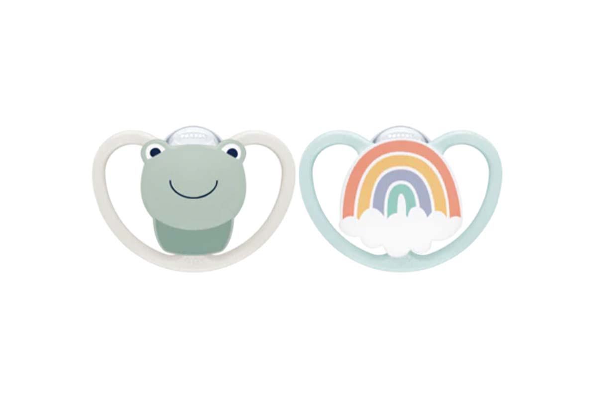 Zwei Schnuller nebeneinander, der linke hat ein Frosch-Design, der rechte einen Regenbogen, weißer Hintergrund
