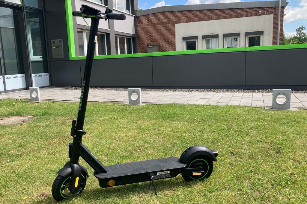 E-Scooter auf einer Wiese vor einem Bürogebäude stehend