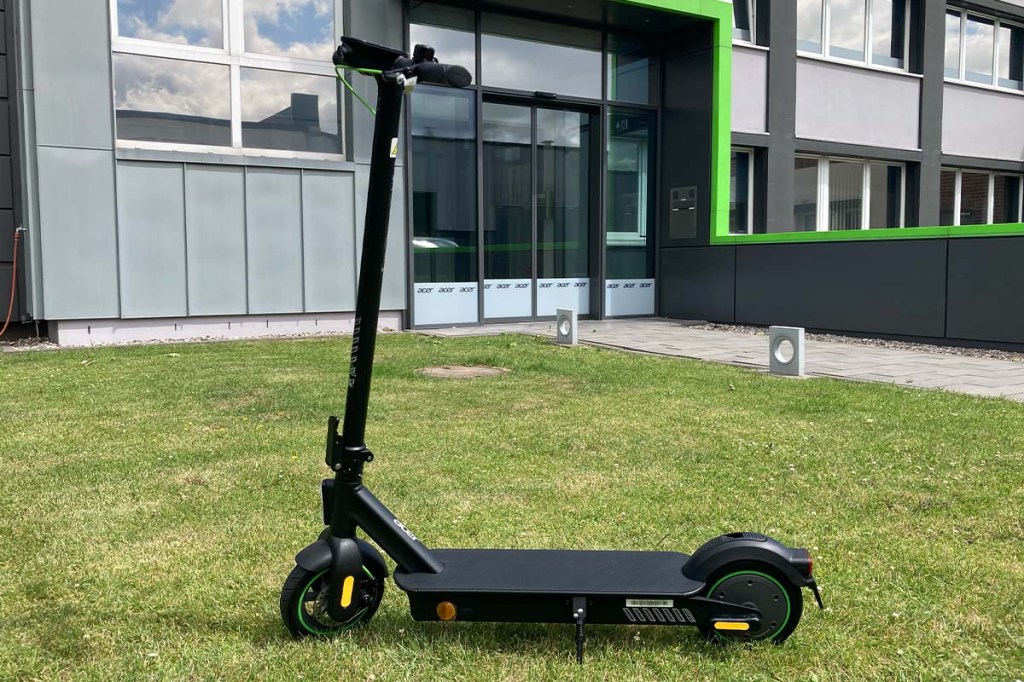 E-Scooter auf einer Wiese vor einem Bürogebäude stehend