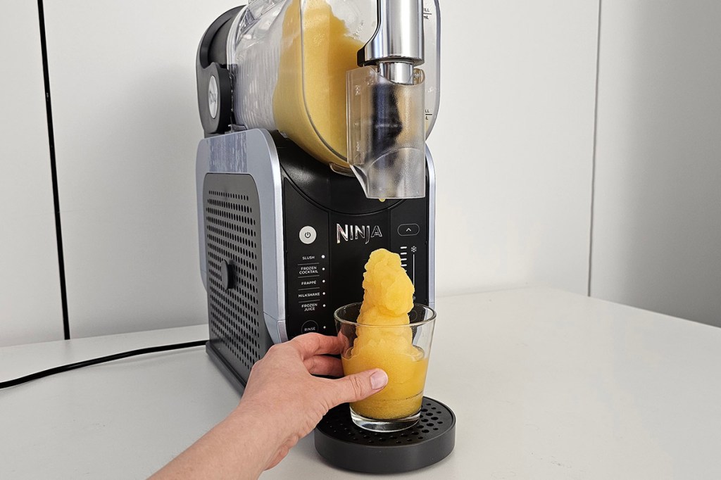 Gelber Slush fließt aus Maschine in Glas
