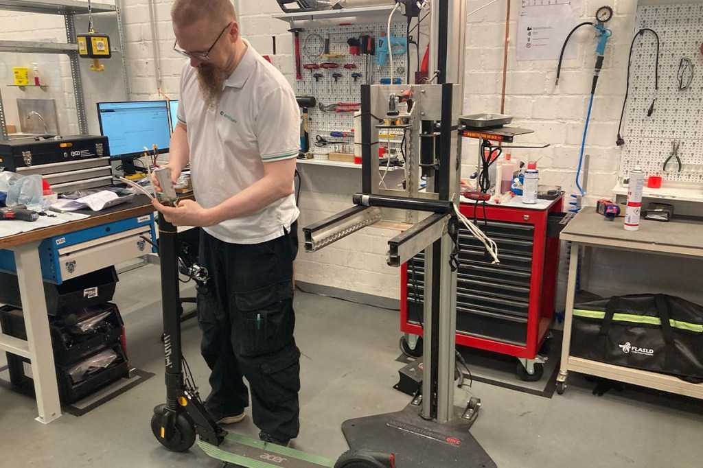Mann in einer Werkstatt, er repariert einen E-Scooter