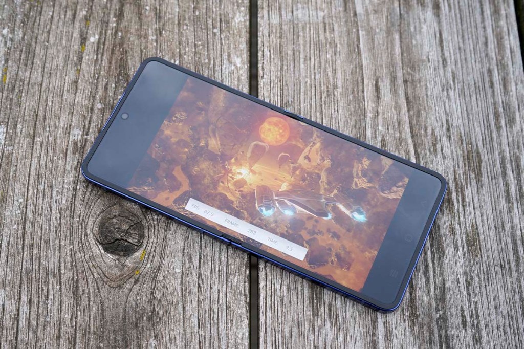 Ein Smartphone liegt eingeschaltet auf einem Holztisch.