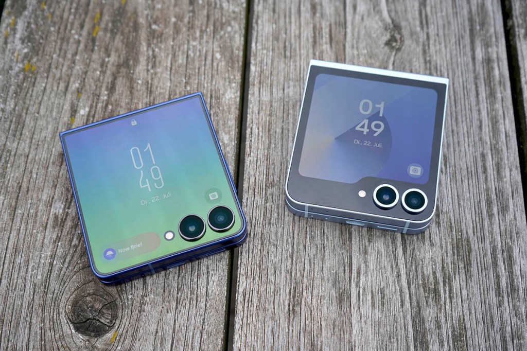 ZWei Samsung-Klapphandys liegen zusammengeklappt nebeneinander auf einem Holztisch.