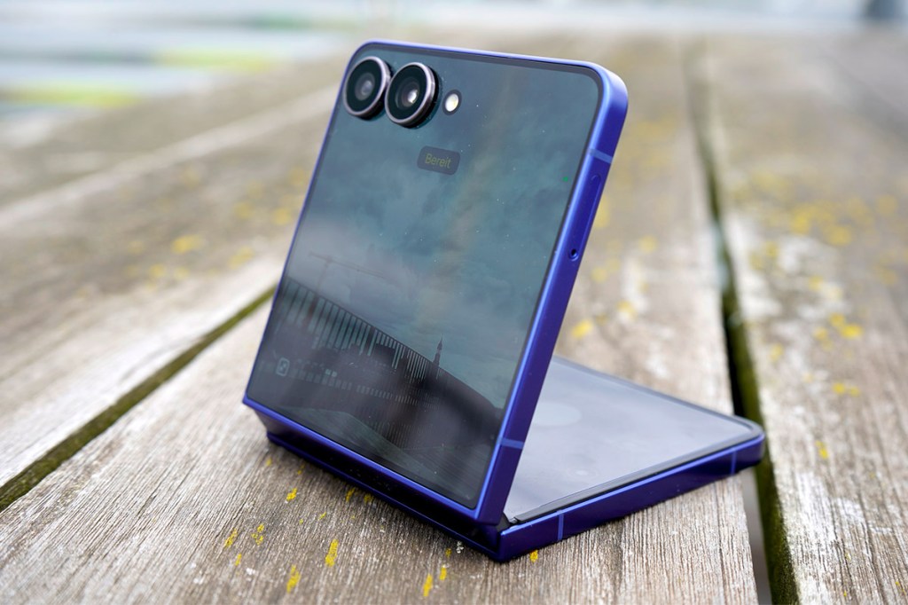 Das Samsung Galaxy Z Flip7 steht halb aufgeklappt auf einem Holztisch.