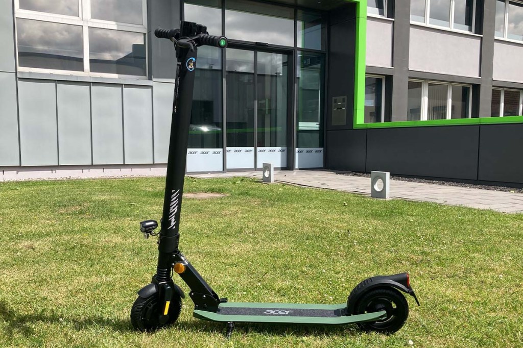 E-Scooter auf einer Wiese vor einem Bürogebäude stehend